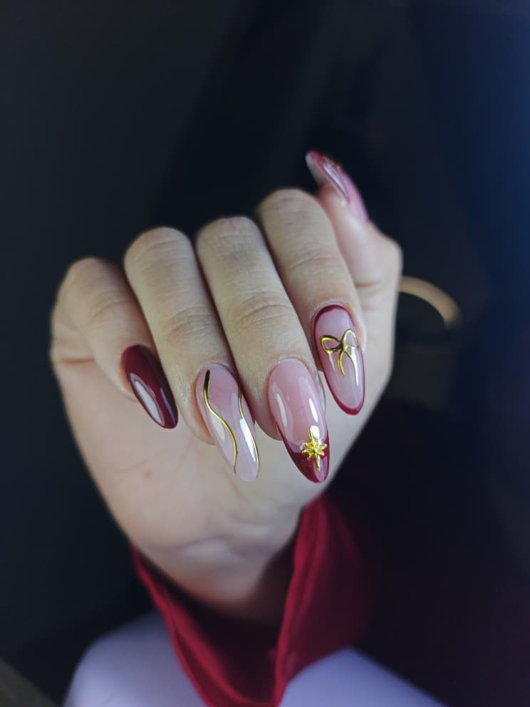 Manicura borgoña con lazo y estrella dorada